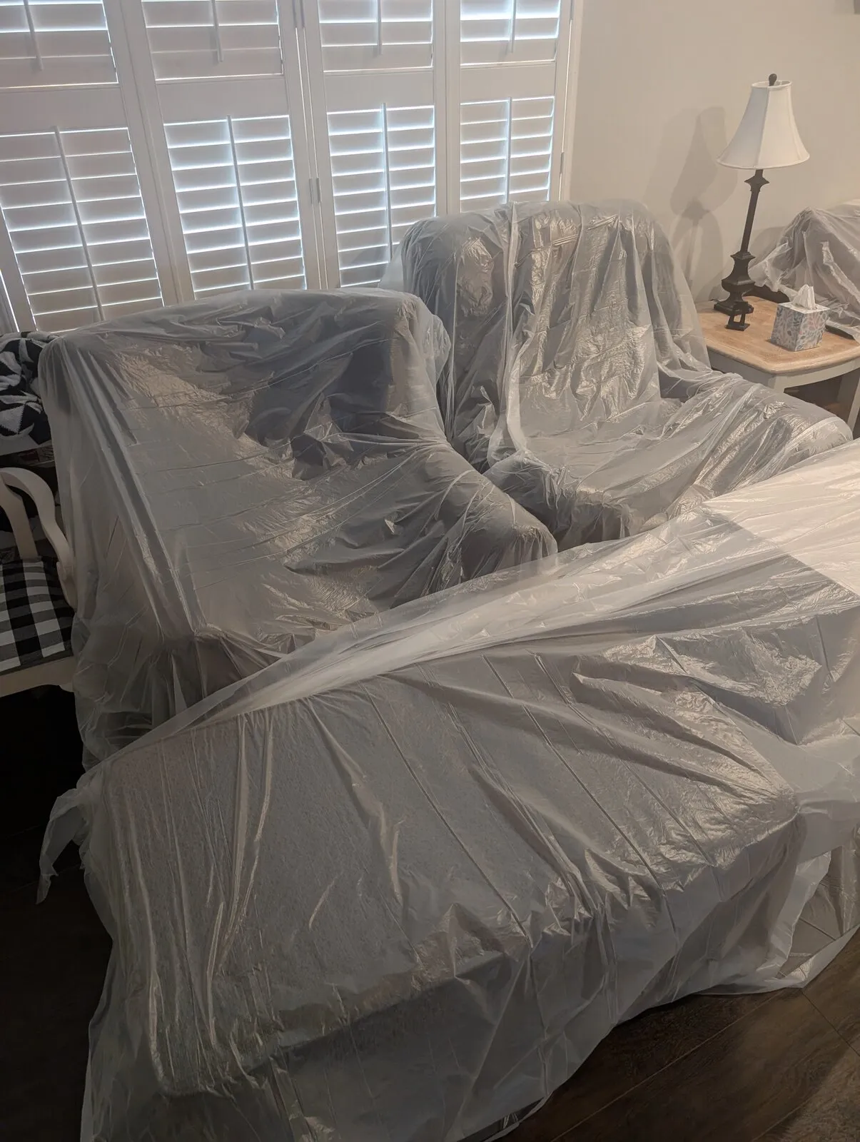 A bed and nightstand wrapped in plastic sheeting.