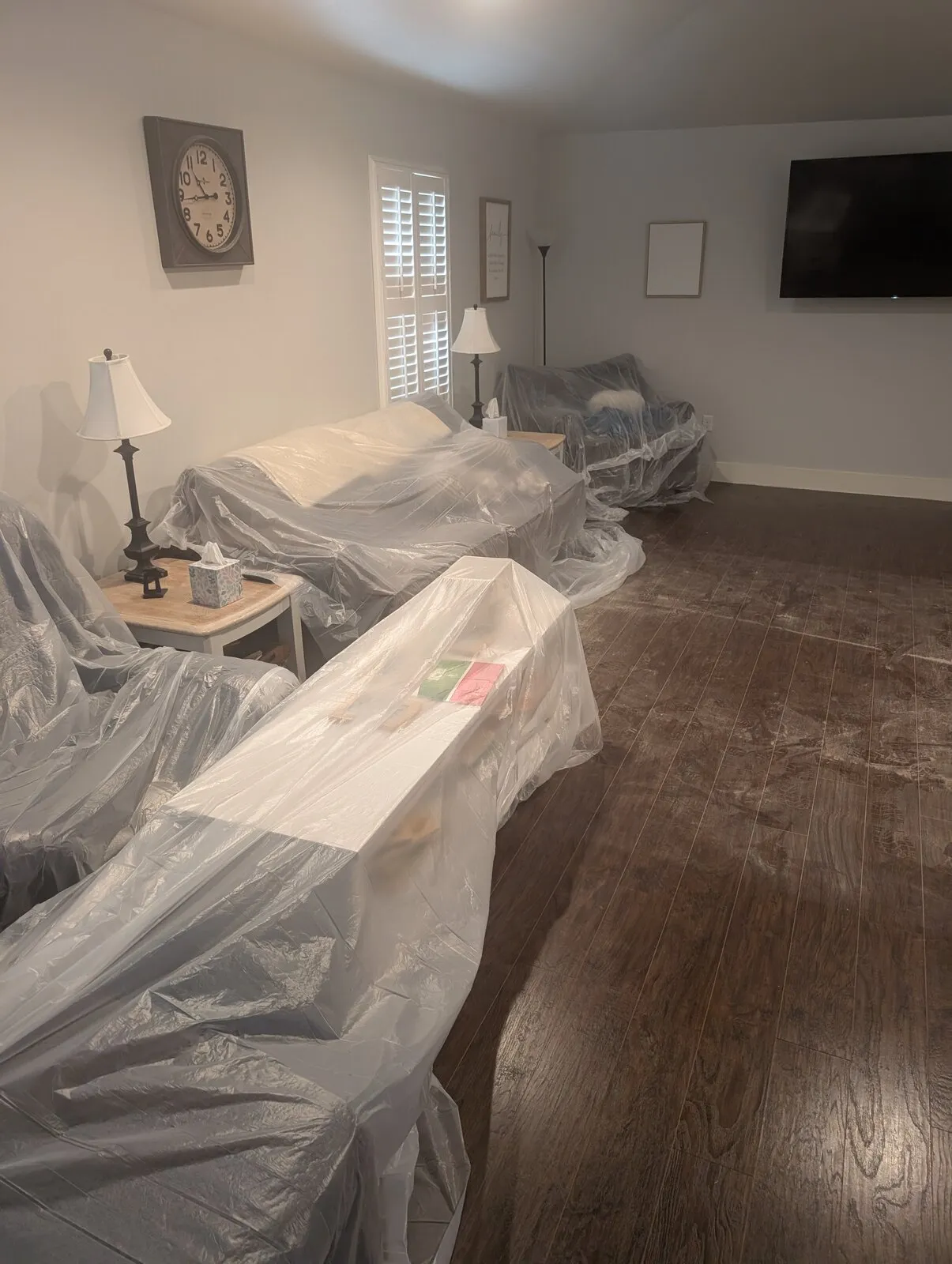 Living room furniture covered in plastic sheeting along one wall.