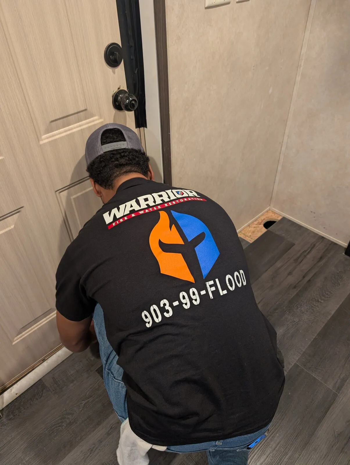 A technician kneeling at a doorway threshold to check the flooring.