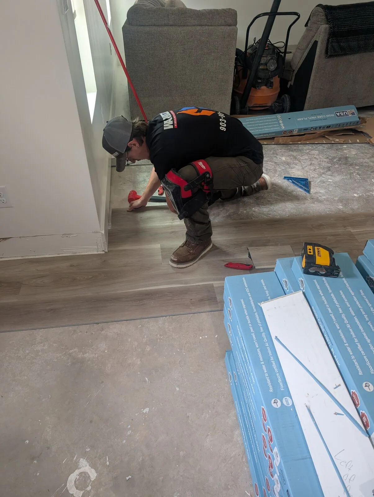 A technician kneeling on floor protection with hand tools laid out beside him.