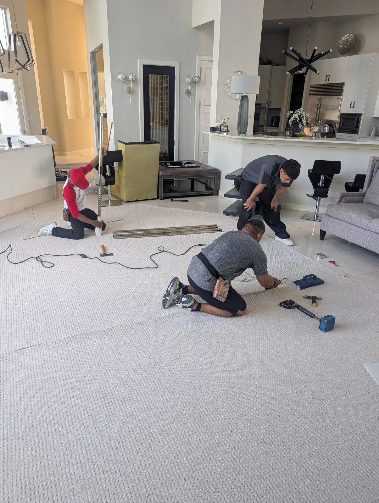 Two technicians working on the floor of a cleared living room.