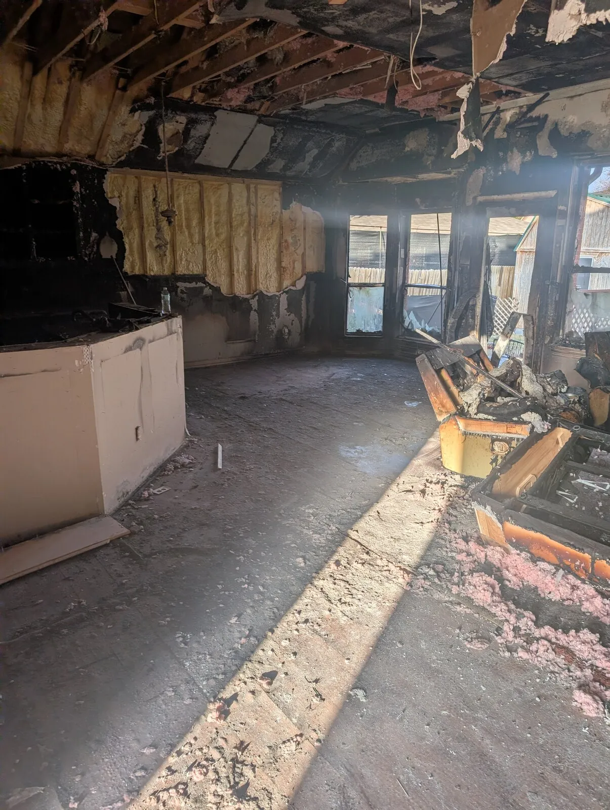 A kitchen with the ceiling burned away to the joists and insulation hanging down.
