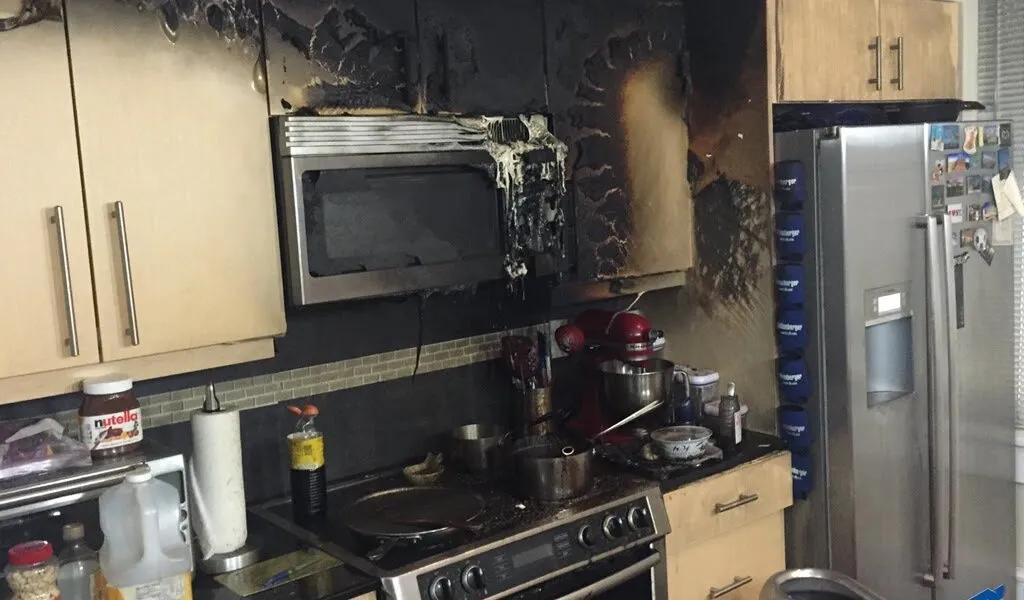 Soot spread up the wall and cabinets above a kitchen range.