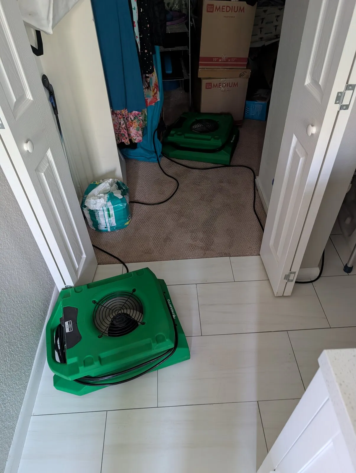 An air mover set in a bathroom doorway with its cord run back into the hall.