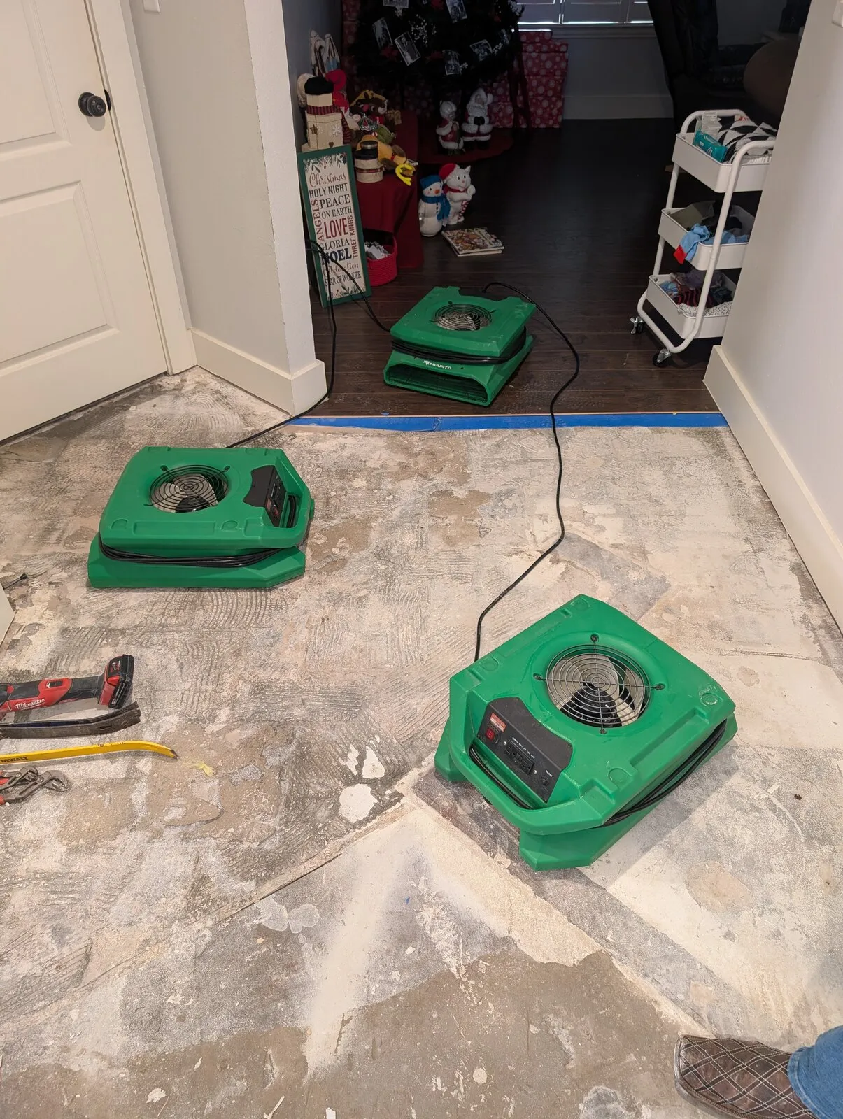 Air movers running on a bare concrete slab after the flooring was removed.