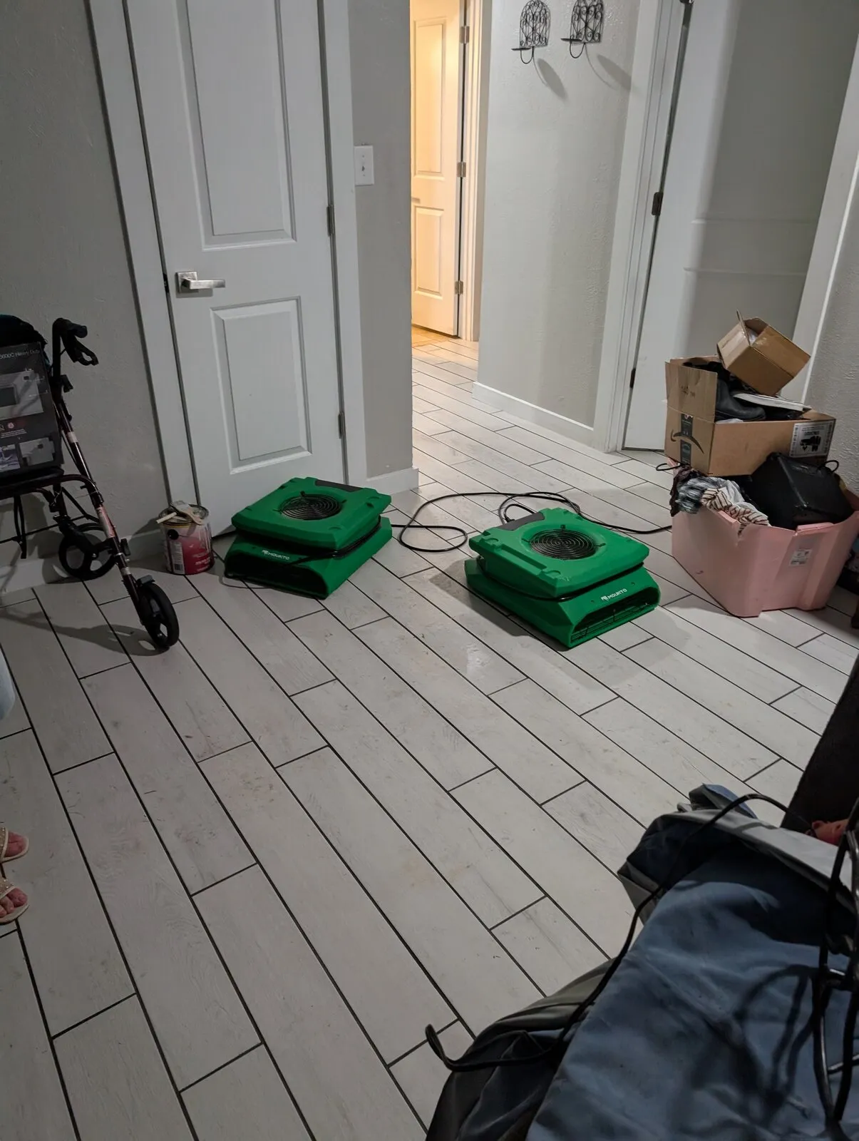 Two air movers running on a tile floor between rooms.