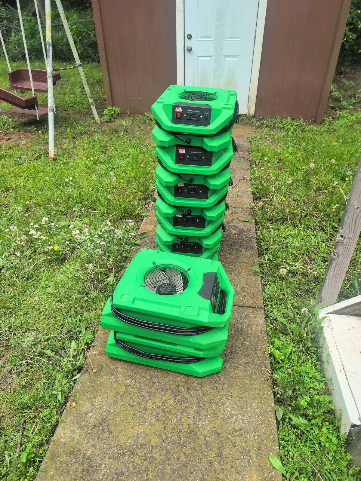 Air movers stacked outside a front door before they are carried in.