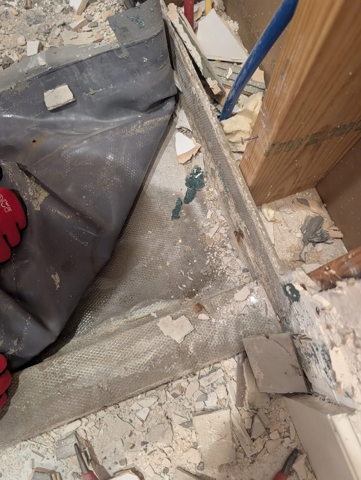 Plastic sheeting hung beside a flood cut, with debris on the floor below.