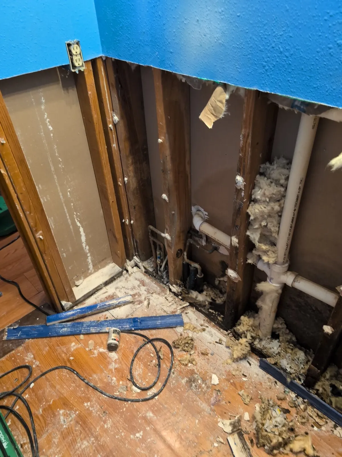 Drywall cut back to the studs along two walls of a room.
