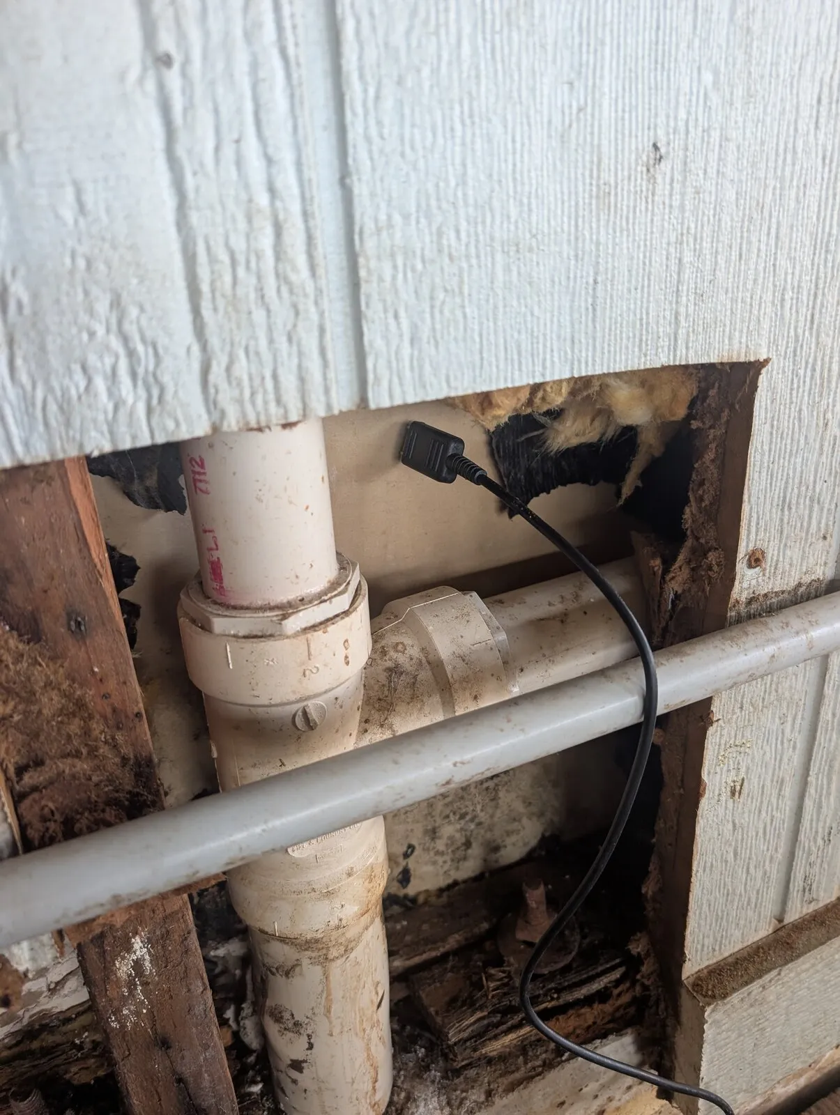 Plumbing running through an opened wall cavity with staining around it.